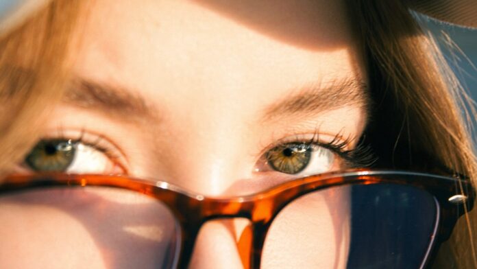A woman's eyes peek over glasses.