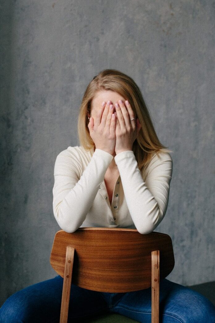 woman in white long sleeve shirt covering her face