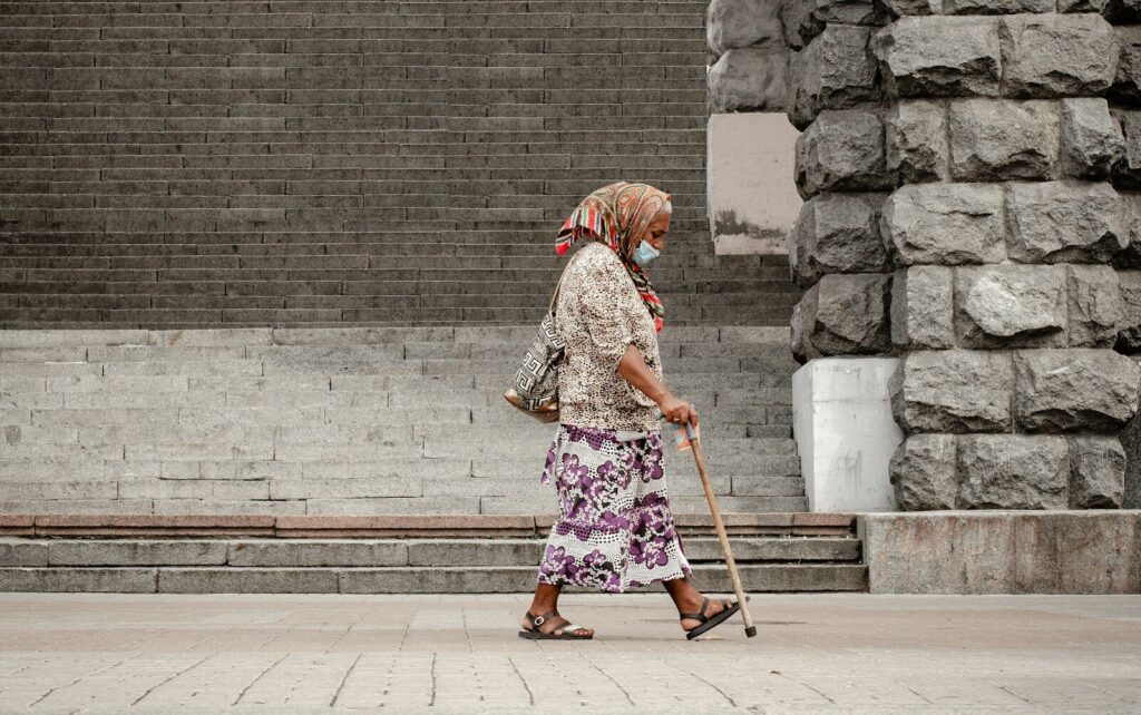 woman in brown and white floral dress walking on sidewalk during daytime