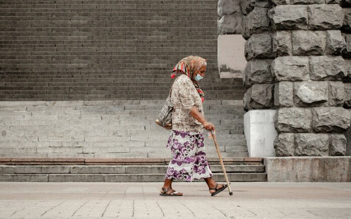 woman in brown and white floral dress walking on sidewalk during daytime